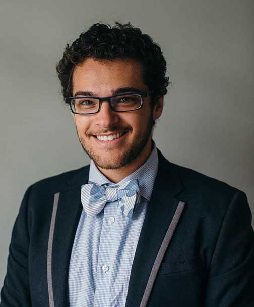 Brent Monseur smiles, wearing a suit jacket with a light blue shirt and bowtie