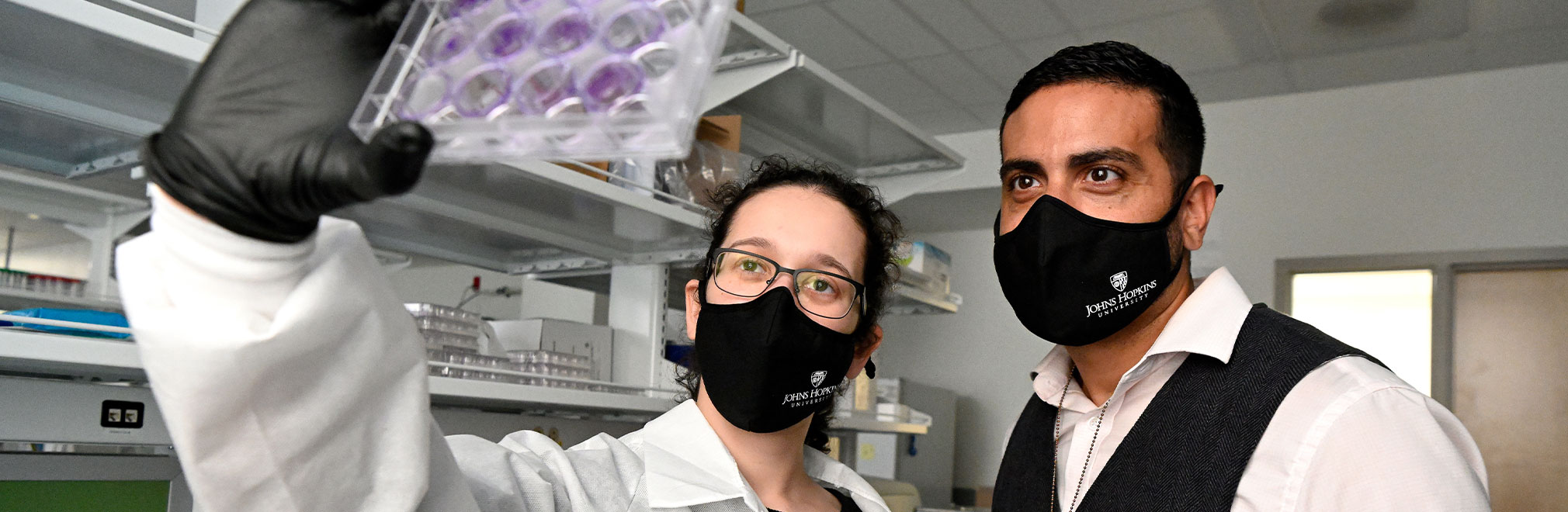 Two people looking carefully at laboratory slides.