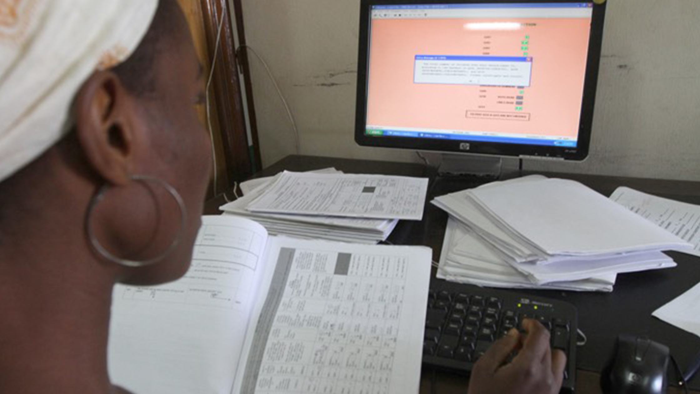 Recent Publications, woman using a computer and books to do research