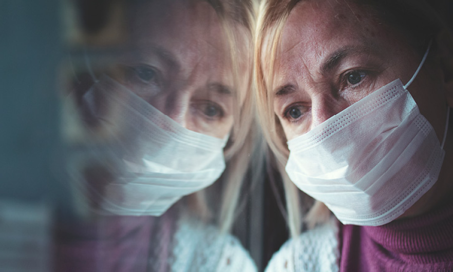 Woman wearing mask staring out window