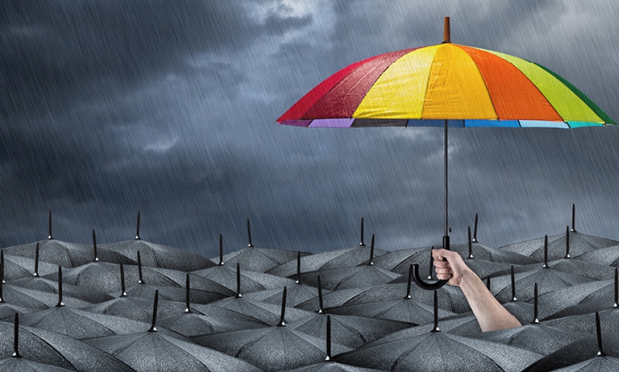 A person holding a colorful umbrella above a sea of black umbrellas in the rain.