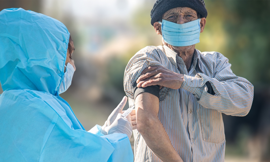 A health care provider gives man a COVID vaccine