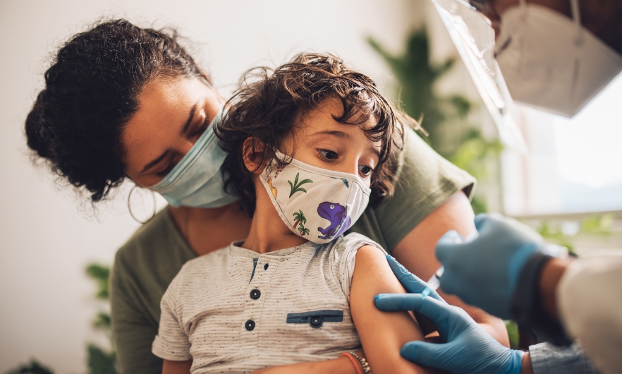 Child being held by parent while getting vaccinated