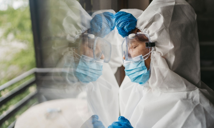 Tired health care working leaning against glass