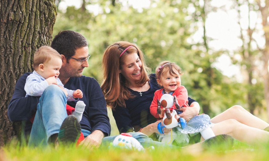 Young family sitting by a tree