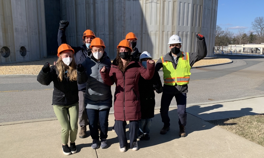 group of students in hard hats and masks in front of water treatment facility