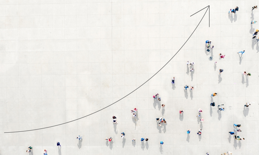 Aerial view of people on a graph beneath an arrow indicating an upward spike