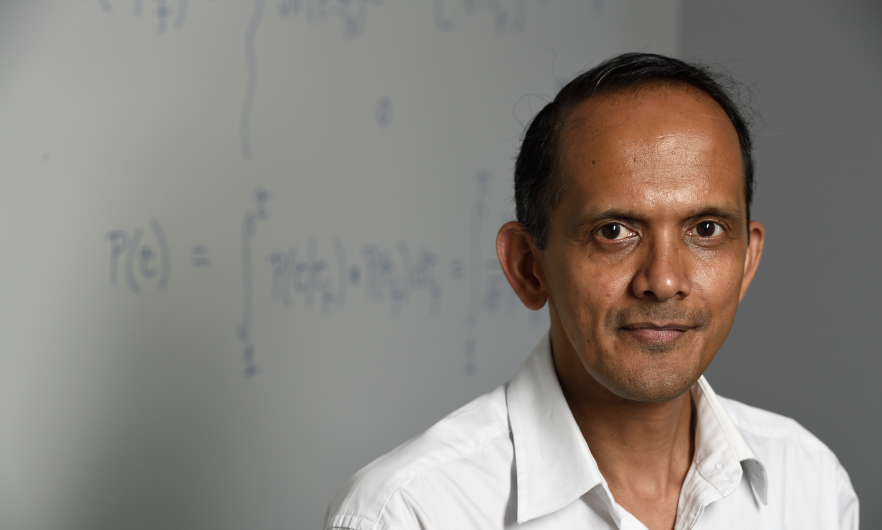 man smiling standing in front of chalkboard with mathematical equations