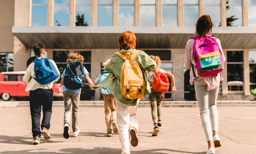 Students eagerly run towards their school to start class