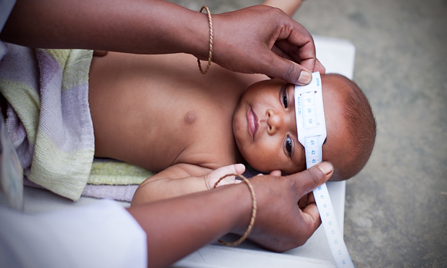 3-month old baby measured for head circumference in the home with tape measure