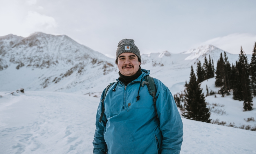 young man in teal coat in snowy landscape