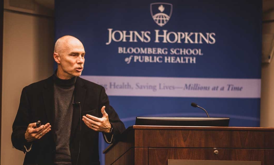 James Berger stands to the slide of a lecture, gestruring with his hands