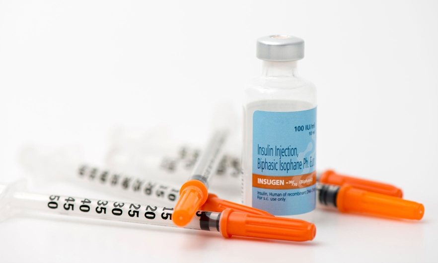 a vial of insulin with three syringes resting next to it