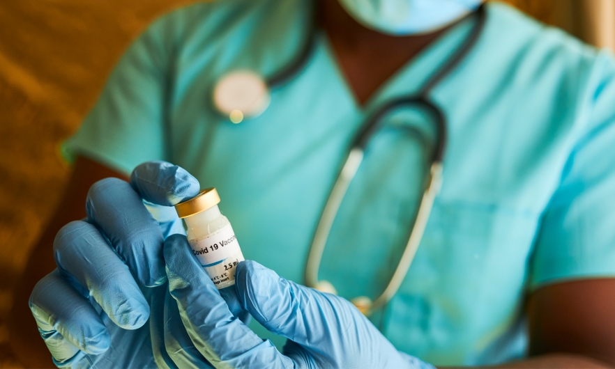 Close-up of a medical provider's gloved hands holding a vaccine vial