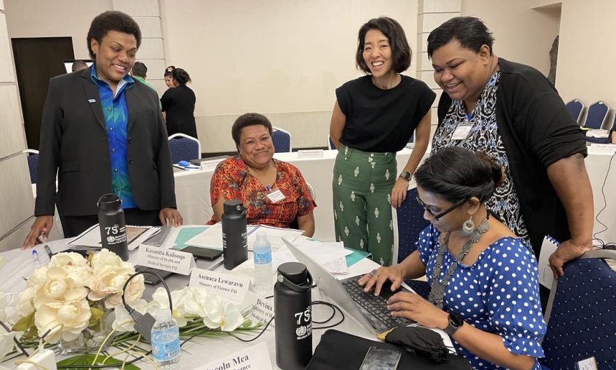 A group of smiling people around a table covered with papers