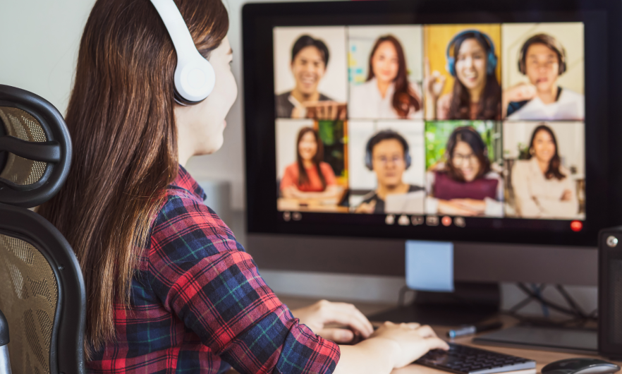 Woman in front of computer monitor displaying 8 people in an online course discussion