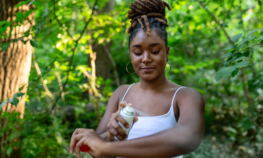 Woman applying insect repellent to her arms.