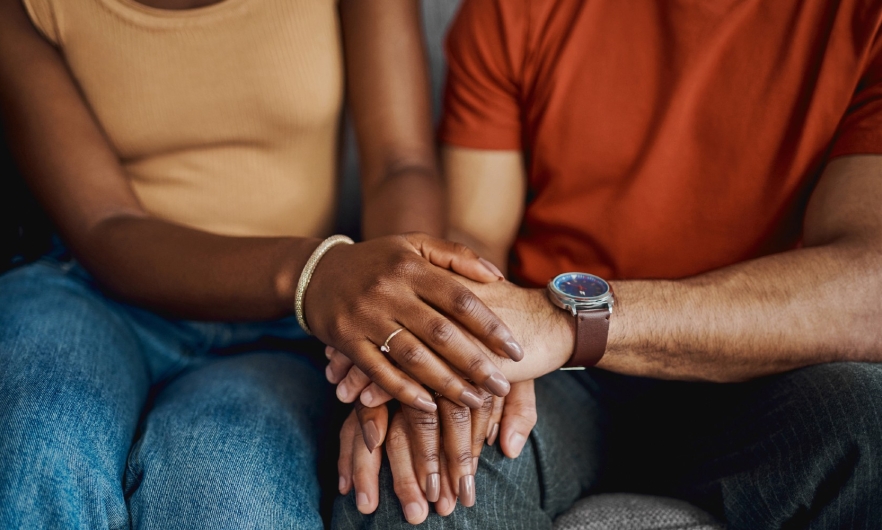 image from neck down of two adults holding hands