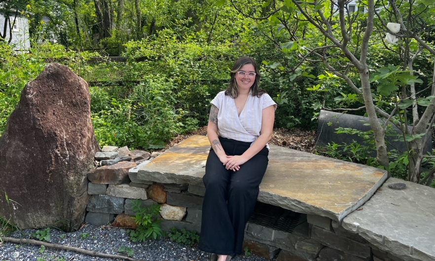 Hannah Davidson sits outside on a stone bench 