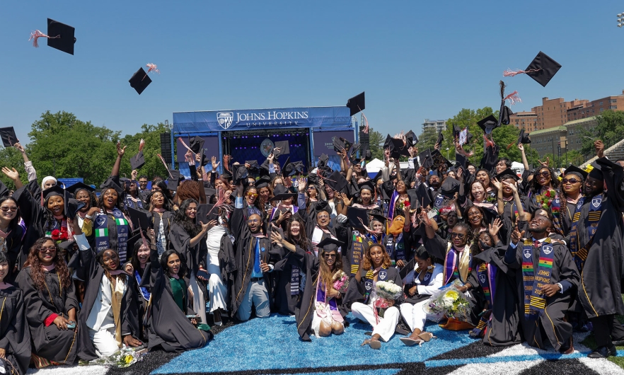 Bloomberg School graduates toss their caps in the air