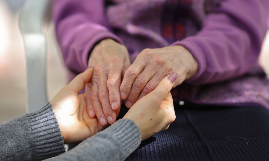 A youthful pair of hands holds an elderly pair of hands