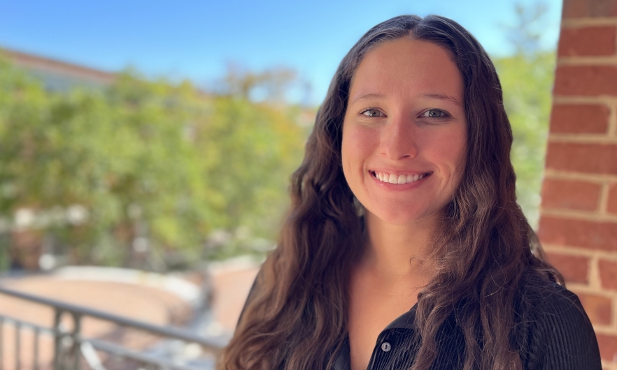 Head shot of young woman with long hair with campus in the background