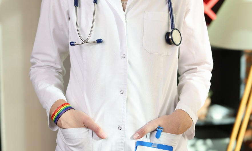 A doctor in a white lab coat wearing a rainbow bracelet