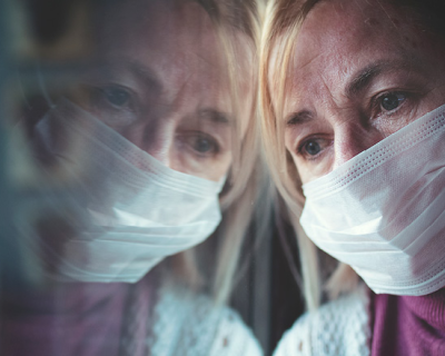 Woman wearing mask staring out window