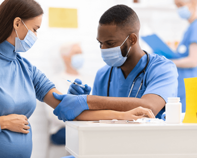 A pregnant woman gets a vaccine from a health care worker