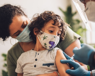 Child being held by parent while getting vaccinated