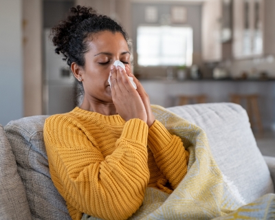 woman sitting on the couch blowing her nose