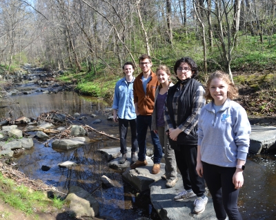 Alexander Holt, Zachary Ellis, Amanda Hinton, Marissela Gomez, and Chloe Frantz stand on rocks in Stony Run Creek.