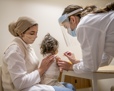 Mother holding child on her lap while she receives vaccine