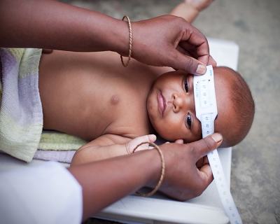 3-month old baby measured for head circumference in the home with tape measure