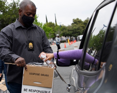 Mike Davis, associate special agent in charge for the Los Angeles division of the Drug Enforcement Administration, holds a container as a driver drops off bottles of prescription drugs to be boxed for disposal during the 20th National Prescription Drug Take Back Day at Watts Healthcare on April 24, 2021.