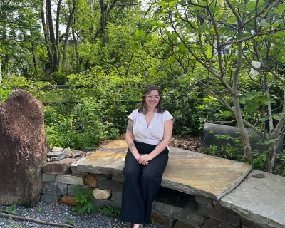 Hannah Davidson sits outside on a stone bench 