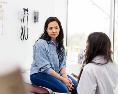 a young person sits and receives bad news from their doctor