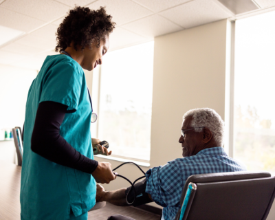 health worker taking blood pressure of seated patient