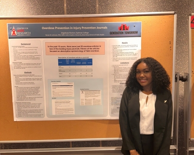 Presenter, Angelease Bunton standing in front of her poster presentation titled, "Overdose Prevention in Injury Prevention Journals."