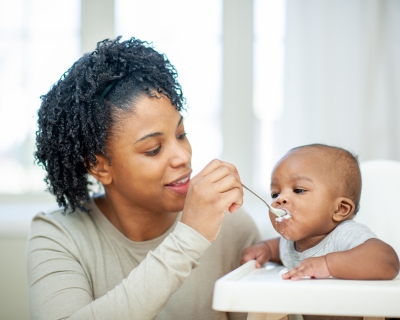 A  baby boy in his highchair as his Mother feeds him