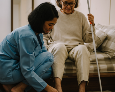 Image of middle aged woman helping an older woman out of bed