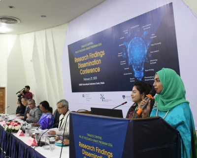 Two Bangladeshi women speak in front of a research conference