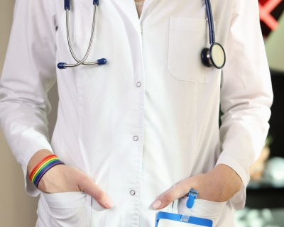 A doctor in a white lab coat wearing a rainbow bracelet