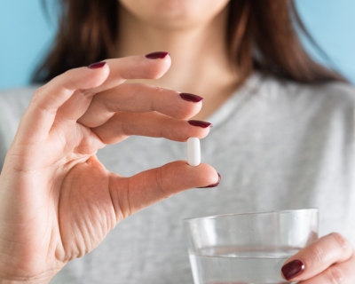 woman holding a pill - face not shown