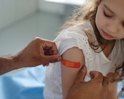 A doctor places a bandaid on the arm of a girl who has just received a vaccine.