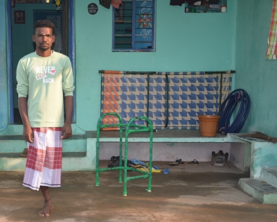 Muthukutti, a 23-year-old man from Surangudi, India, stands outside his home.