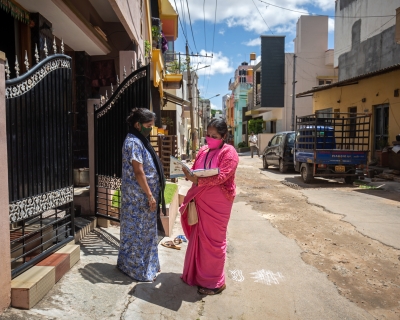Sunitha, an Accredited Social Health Activist (ASHA) checks on a pregnant woman outside her house on May 18, 2021, in Mysuru, India.