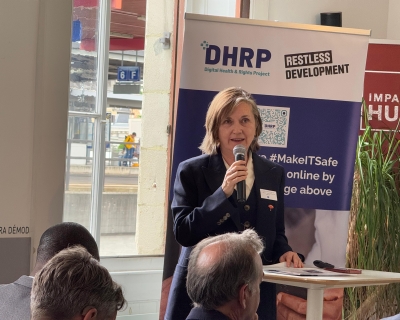 Photo of Professor Meg Davis holding a microphone and speaking before an audience for a sidebar event at the World Health Assembly.