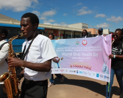 A saxophone player wearing a white t-shirt plays in a parade marking World Oral Health Day in Zambia.