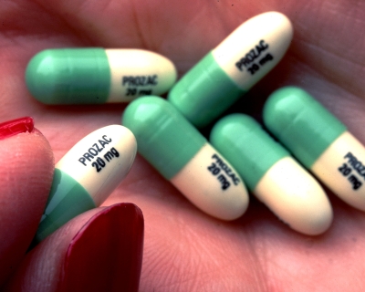 A person holds Prozac tablets in their palm.